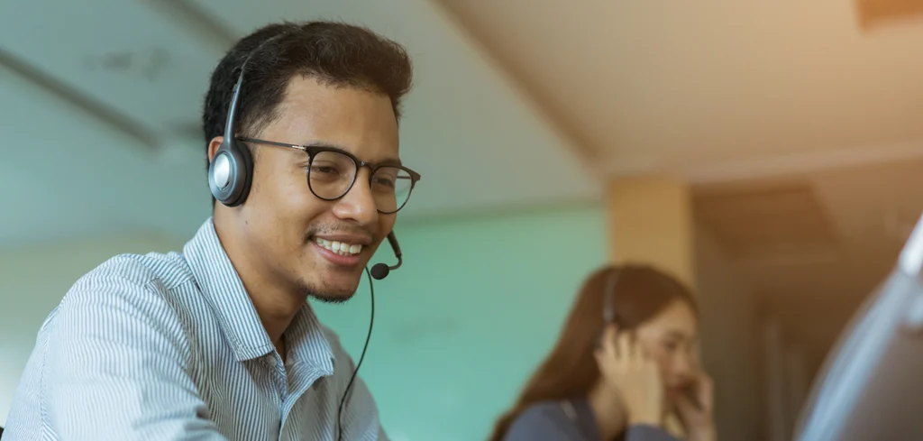 call center man wear headset for talking with customer and working with woman colleague help desk support with voip solutions.