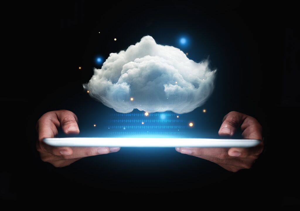hands holding a tablet with imaginary numbers floating above it going up toward a life-like cloud