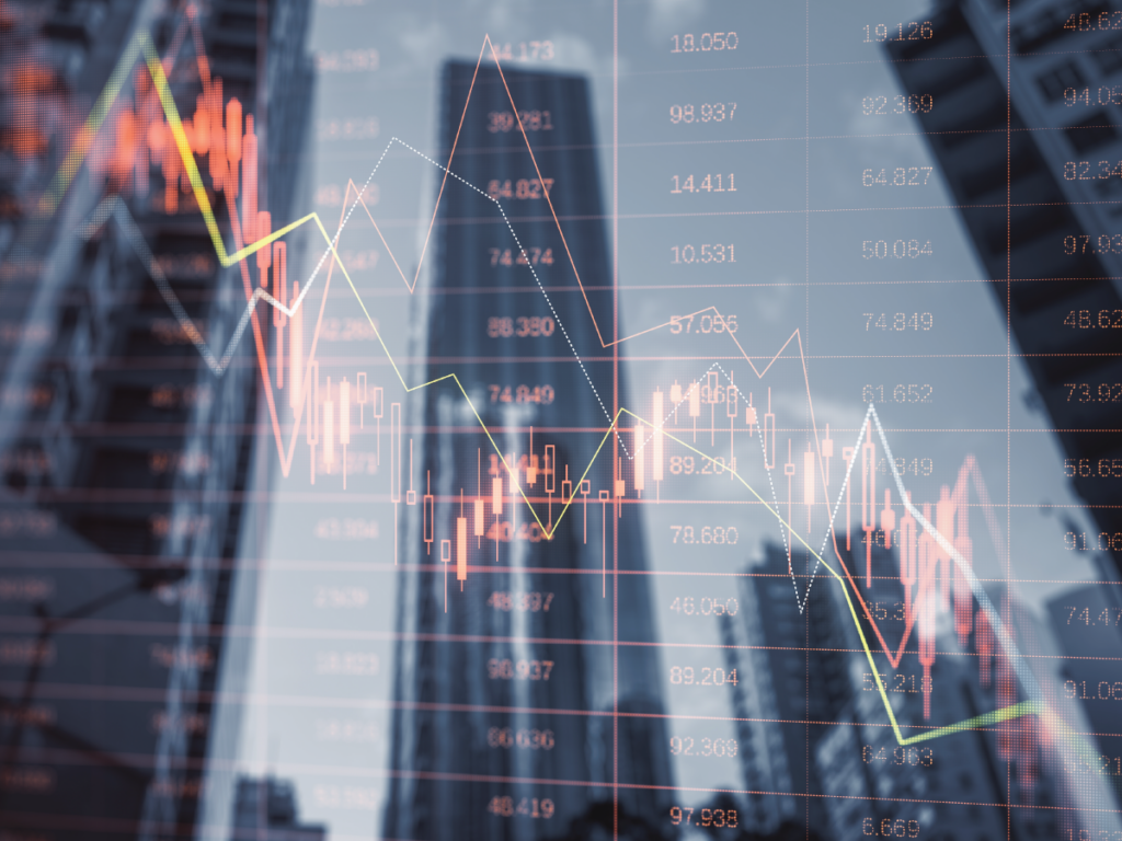 stock market declining chart overlayed over a photo of business skyscrapers.